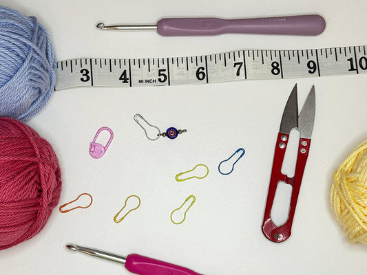 Photo of the 5 (plus one bonus) tools that crocheters must have (yarn, crochet hooks, scissors, tape measure, and stitch markers)